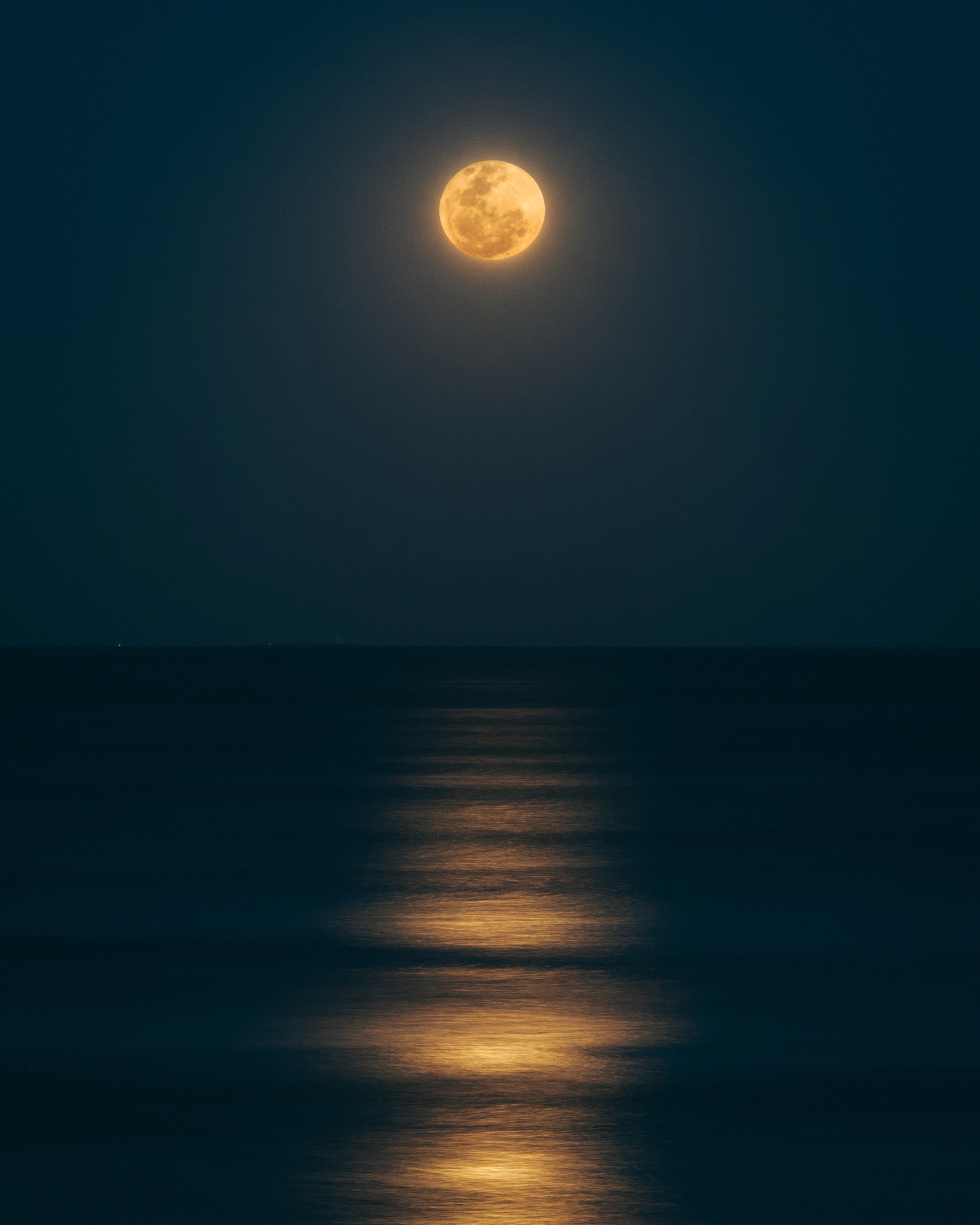 海に満月の光が映る夜の風景